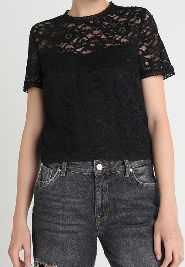 Sort blondebluse med blomsterprint og korte ærmer, med tekstureret stof og rund halsudskæring, båret sammen med slidte sorte jeans.