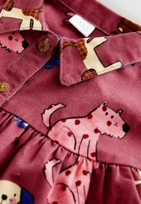 Baumwollkleid in Burgunderrot mit Hunde-Mustern. Verfügt über einen Kragen, Knöpfe und eine geraffte Taille. Weicher, strukturierter Stoff mit bunten Drucken.