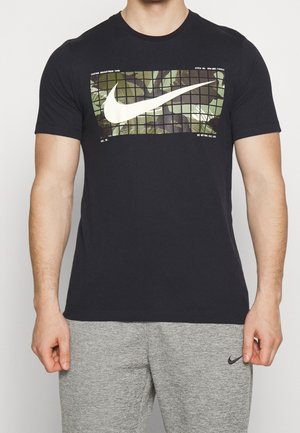 T-shirt nera in cotone, con un motivo camouflage e un grande logo Nike bianco sul davanti. Maniche corte e design a girocollo.