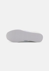 Hvit sneakers med en teksturert gummisåle med horisontale rygger. Overdelen har lyseblå detaljer og en glatt finish.