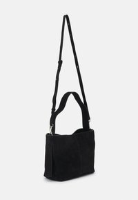 Czarna zamszowa torebka na ramię z szerokim otwarciem, regulowanym paskiem i kontrastującym przeszyciem. Posiada jedną główną komorę.