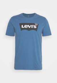 T-shirt Levi's bleu manches courtes avec logo Levi’s noir et blanc imprimé sur la poitrine sur un fond uni.