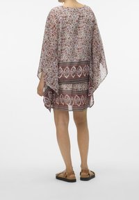 Kaftan floral transparent à manches courtes, imprimé multicolore, coupe fluide, avec un motif contrastant en bordure à l'ourlet. Tissu léger.