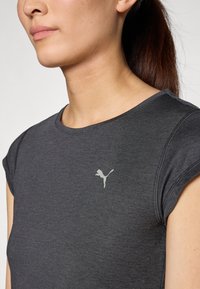Camiseta atlética negra de manga corta, con tejido suave, escote redondo y un pequeño logotipo gris claro en el pecho.