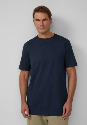 Marineblauwe katoenen t-shirt met korte mouwen, ronde halslijn en subtiele logodetail op de borst, gecombineerd met lichtgekleurde sweatpants.