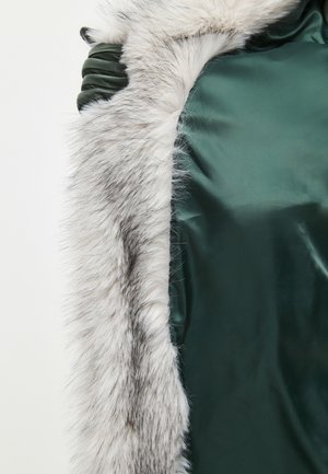 Grüner Satin-Stoff mit einem plüschigen, grauweißen Pelzbesatz. Besitzt eine glatte Textur und einen leichten Glanz. Offenes Design, das luxuriöse Materialien betont.