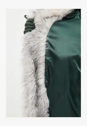 Zielony satynowy materiał z pluszowym, szarym-białym futrem. Posiada gładką teksturę i delikatny połysk. Otwarty design, podkreślający luksusowe materiały.