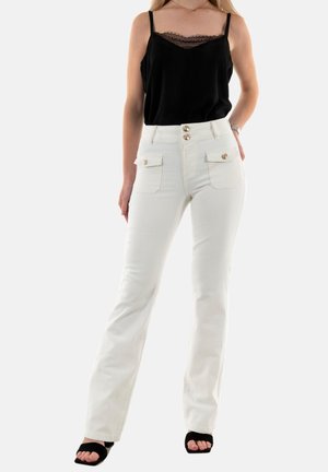 Jean flare blancs avec deux poches avant, accents de boutons dorés et taille ajustée, associés à un débardeur en dentelle noire.