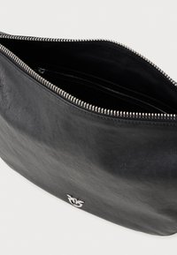 Melnas ādas rokassomi ar sudraba rāvējslēdzēju, daļēji atvērtu, kurā redzams melns auduma iekšpuses apdare un neliels sudraba putna emblēma priekšpusē.