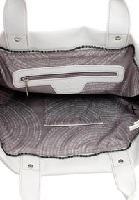 Intérieur d'un sac fourre-tout en cuir blanc, avec une texture lisse, une poche zippée et une doublure en tissu à motifs avec du texte imprimé et des logos.