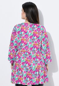 Blomsterkjole med pink og lilla blomster på en turkis baggrund, med lange ærmer og en lagdelt, udskåret kanten.