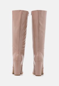 Stivali rosa lucidi alti fino al ginocchio con tacco quadrato. Presentano una zip sul retro per la chiusura e una superficie liscia e sinuosa.