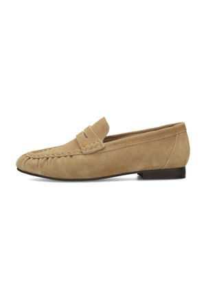 Mocasín beige de ante con punta mocasín cosida, tira decorativa y suela plana negra, mostrado de perfil sobre fondo blanco.