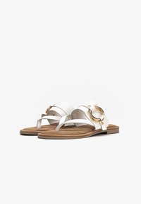 Bílé kožené sandály s plochou podrážkou, zdobené zlatým kroužkem a překříženými pásky, s měkkou tanovou stélkou pro pohodlí.