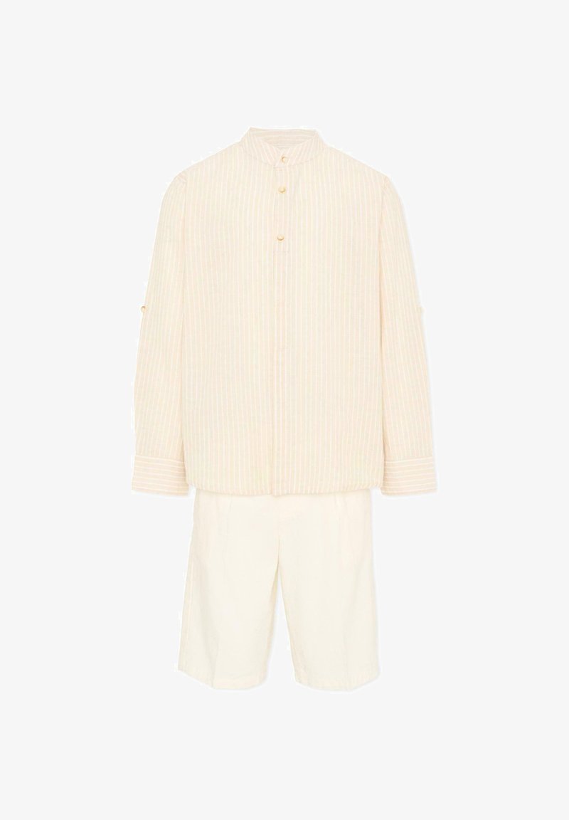 Chemise crème à manches longues avec rayures verticales et boutons dorés, associée à un short blanc mi-long, sur fond blanc.
