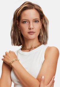 Gold metal jewelry set including a chunky chain necklace, matching bracelet, and hoop earrings, displayed against a white background.