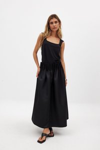 Conjunto negro de dos piezas que incluye una blusa sin mangas y una falda plisada de cintura alta. El material tiene una textura suave y un acabado mate.