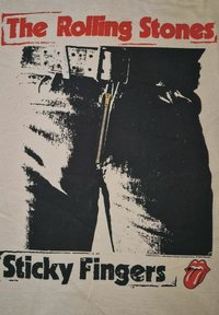 Hvit t-skjorte med et svart-hvitt grafisk bilde av denimbukser med glidelås. Teksten "The Rolling Stones" og "Sticky Fingers" står i fet rød og svart.