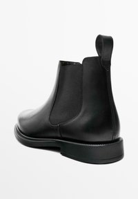 Schwarze Leder Chelsea-Boots mit elastischen Seiteneinsätzen, glatter Oberfläche, robuster Sohle und einer Schlaufe an der Ferse für einfaches Anziehen.