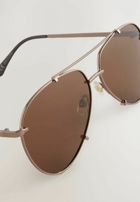 Bruine aviator-zonnebrillen met een metalen frame en verstelbare neuspads. Strak, hoekig ontwerp met dunne zwarte pootjes.