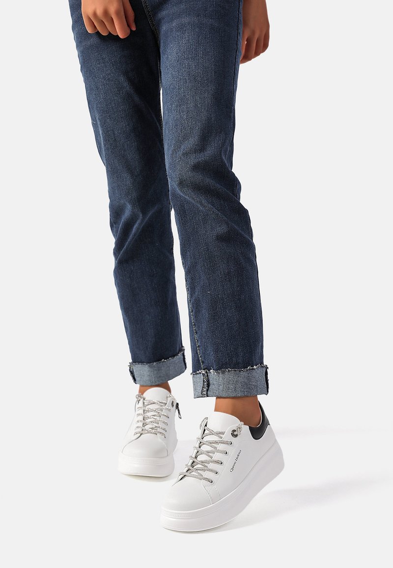 Sneaker bianche con occhielli in metallo e lacci texture, presentano un elegante accento nera sul tallone. Indossate con jeans di denim arrotolati.