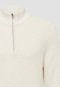 Jasnobeżowy sweter z dzianiny z wysokim kołnierzem, wyposażony w krótki zamek błyskawiczny. Tekstura jest prążkowana, a design prosty i funkcjonalny.