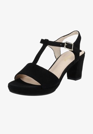 Sandales à talons en suède noir avec un design à T, bout ouvert et une large sangle de cheville avec une boucle en argent. Le talon est de forme bloc.