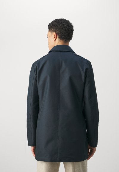 Marineblauer Mantel mit strukturiertem Stil, mit einem abgesetzten Revers und einer glatten, matten Oberfläche. Lange Ärmel und eine taillierte Silhouette.