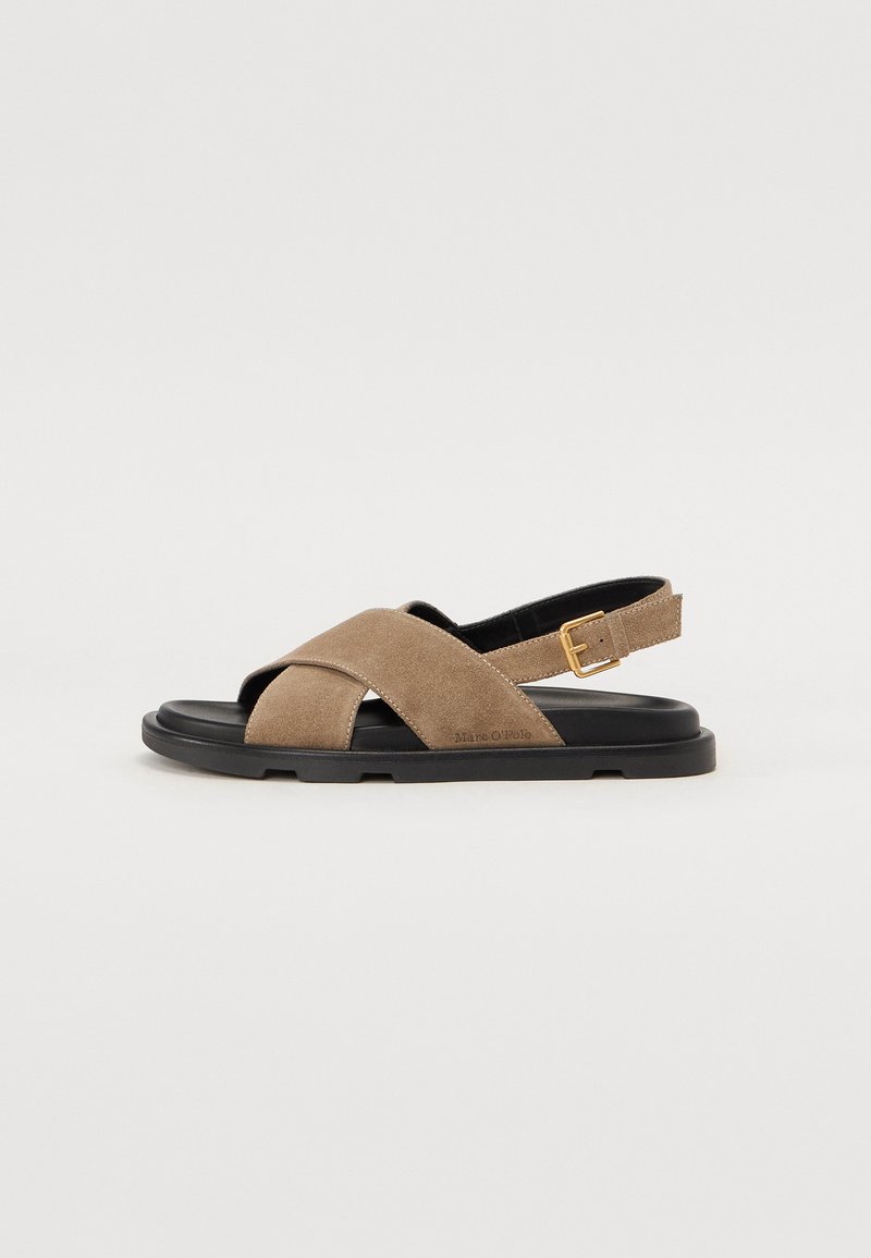 Brown suede sandal with a cross-strap design, open toe, adjustable ankle strap, and a black rubber sole. No patterns or embellishments.