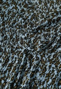 Tissu bleu avec imprimé floral noir et marron, présentant des sections froncées et plissées créant des plis et des drapés texturés.