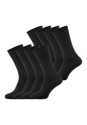 Set van acht effen zwarte sokken tot halverwege het onderbeen, gelijkmatig verdeeld in twee rijen tegen een witte achtergrond.