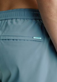 Pantaloni shorts azzurri chiari realizzati in tessuto morbido, con una cintura elastica, una tasca posteriore e un piccolo etichetta con logo cucita.