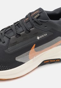 GORE-TEX løpesko med overdel i svart tekstil, oransje og hvite detaljer, mesh-panel og en teksturert, polstret såle.
