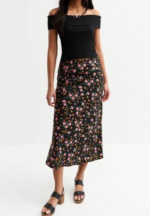 Zwarte bloemenrok met roze en gele bloemen, gecombineerd met een geribd zwart off-shoulder topje en zwarte sandalen met brede blokhak.