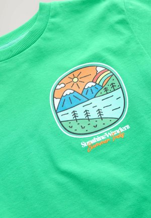 Green cotton t-shirt featuring a landscape graphic with mountains, trees, sun, and a rainbow. Text reads "Sunshine Wonders Summer Tracks."