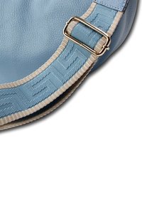 Sac en cuir bleu clair avec une bordure texturée et une boucle argentée sur la sangle réglable. Le design est arrondi et doux.