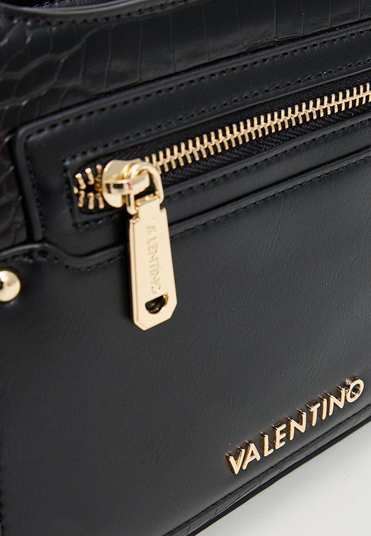 Schwarze, strukturierte Lederhandtasche mit goldenen Beschlägen, ausgestattet mit einem hervorgehobenen Reißverschlussgriff und einem geprägten Markennamen, der ein elegantes Design präsentiert.