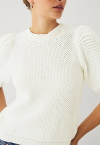 Maglione bianco a maglia con un design testurizzato e traforato, maniche corte a palloncino e scollatura a costine, con una vestibilità morbida.