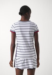 Vestido blanco a rayas con líneas horizontales en azul marino, mangas cortas y acentos rojos. Corte ajustado, dobladillo plisado y material ligero para mayor comodidad.