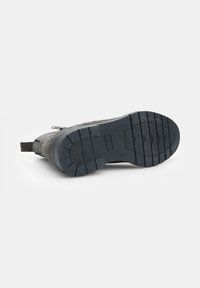 Stivale alla caviglia in suede grigia con suola in gomma nera texture, zip laterale e accenti grigio scuro. Parte superiore liscia senza motivi visibili.