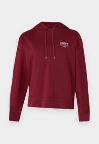 Sudadera con capucha de color burdeos, con un bolsillo frontal, cordones ajustables y texto de logo blanco en el pecho, fabricada con un tejido suave.