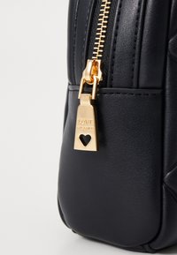 Black faux leather bag with a quilted design, a gold zipper, and a heart-shaped lock charm engraved with "LOVE" for detail.