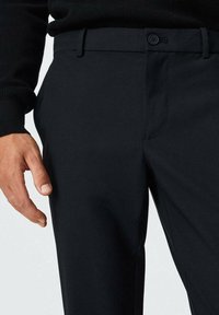 Černé kalhoty z hladké látky mají strukturovaný střih, plochý přední díl, zapínání na jeden knoflík a boční kapsy.