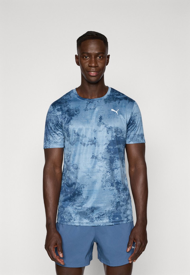 Blauwe sport T-shirt met een gestructureerd, abstract ontwerp en een witte logo op de linkerborst. Korte mouwen en een ronde hals.
