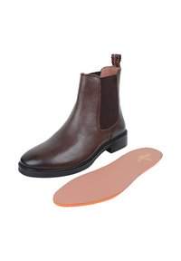 Brązowe skórzane botki Chelsea z elastycznymi panelami bocznymi, o zaokrąglonym nosku i niskim czarnym obcasie; zawierają wyjmowaną wkładkę w kolorze beżowym i pomarańczowym.