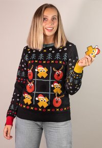 Black sweater with colorful Christmas-themed appliqués, including reindeer and ornaments, and red and yellow ribbed cuffs.