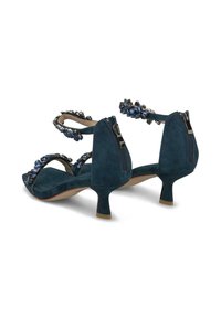 Zapatos de tacón de ante color aguamarina con un bajo stiletto, que presentan gemas decorativas azules y negras en las correas y un cierre con cremallera en la parte trasera.