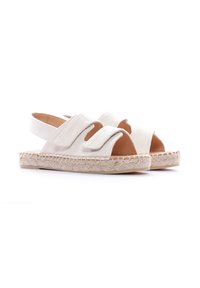 Sandalias de tela blanca con suela de yute similar a una alpargata. Presentan dos cintas anchas y superpuestas y un diseño sin talón para facilitar su uso.