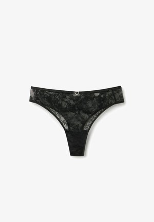 Schwarzer Spitzen-String mit Blumenmustern, einem Seidengürtel und einem kleinen silbernen Herzanhänger in der vorderen Mitte. Strukturierte Spitzen-Details überall.