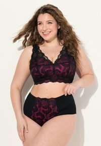 Zwarte en fuchsia kanten bralette met gegolfde randen, gecombineerd met hoge zwarte slips met een kanten deel. Zachte textuur, bloemenpatroon.